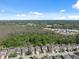 An aerial view of neighborhood homes with tree line and commercial property in the distance at 1250 Halapa Way, Trinity, FL 34655