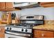 Close-up of a stainless steel gas stove with granite countertops and wooden cabinets at 1250 Halapa Way, Trinity, FL 34655