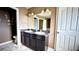 Bathroom featuring dual sinks with dark cabinets and tiled floor at 13066 Painted Bunting Ave, Weeki Wachee, FL 34614