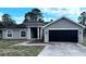 Charming single-story home with a black garage door and inviting front entrance at 13066 Painted Bunting Ave, Weeki Wachee, FL 34614