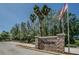 Welcoming Wyndgate community entrance with stone signage, landscaping, and an American flag waving overhead at 1615 Cortleigh Dr, New Port Richey, FL 34655