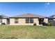 The backyard shows a well-maintained lawn and a simple patio area with outdoor equipment at 1957 Fan Aloe Way, Ruskin, FL 33570