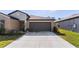 Home featuring a two car garage, well-manicured lawn and verdant landscaping at 1957 Fan Aloe Way, Ruskin, FL 33570