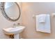 Powder room features a decorative mirror, pedestal sink, and a towel rack with fresh, white towels at 2506 W Ivy St, Tampa, FL 33607