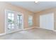 Bright bedroom with neutral walls, carpeted flooring, closet and a set of French doors leading to a balcony at 2506 W Ivy St, Tampa, FL 33607