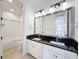 Bright bathroom featuring double sinks with granite countertops and modern lighting fixtures over a large mirror at 2630 Milford Berry Ln, Tampa, FL 33618