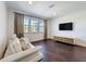 Comfortable living room with dark wood floors, large windows with curtains, and a modern media console at 2630 Milford Berry Ln, Tampa, FL 33618