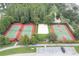 Overhead view of recreational amenities with tennis courts, a volleyball court, and a basketball court next to lush greenery at 3465 Bumelia Ln, New Port Richey, FL 34655