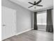 Bright bedroom featuring a ceiling fan, hardwood floors, and gray curtains at 3465 Bumelia Ln, New Port Richey, FL 34655
