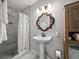 Bright bathroom featuring a marble shower, decorative mirror, pedestal sink, and natural wood storage at 4816 N Highland Ave, Tampa, FL 33603