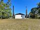 Back exterior view of home with a large yard and mature trees on the property at 6012 Landover Blvd, Spring Hill, FL 34609