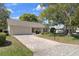 Quaint single-story home featuring brick driveway, attached garage, and manicured front lawn at 6530 Pine Meadows Dr, Spring Hill, FL 34606