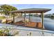 Waterfront outdoor space on canal with dock featuring covered outdoor seating and white picket fence at 6536 Beach Blvd, Hudson, FL 34667