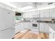 Bright kitchen featuring white cabinets, modern appliances, and wood-look flooring at 7506 Moriah Ave, Brooksville, FL 34613