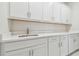 Laundry room featuring white cabinets, countertop space, and a stainless steel sink with modern fixtures at 778 Parsons Mooring Ct, Seffner, FL 33584