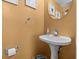 A pedestal sink is set against a gold-colored wall with round mirror and chrome fixtures at 856 Wisconsin Ave, Palm Harbor, FL 34683