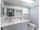 Bright bathroom featuring a double sink vanity, large mirror, and toilet with natural light coming from a window at 8705 Village Mill Row, Hudson, FL 34667