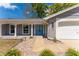 Inviting front entrance featuring a blue double-door, brick siding, and a manicured landscape at 8705 Village Mill Row, Hudson, FL 34667