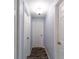 Hallway with tile floors, neutral colored walls, and white doors with updated hardware and contemporary lighting fixture at 8705 Village Mill Row, Hudson, FL 34667