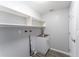 Laundry room featuring upper shelves, stainless steel sink, and white cabinet with access door to the right at 8705 Village Mill Row, Hudson, FL 34667