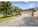 A view of the home's driveway leading up to a two-car garage, surrounded by lush landscaping at 9040 Mark Twain Ln, Port Richey, FL 34668