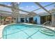 Enclosed pool area with a screened enclosure, a covered seating area, and a sparkling pool for refreshing relaxation at 9040 Mark Twain Ln, Port Richey, FL 34668