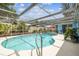 Sparkling pool under a screened enclosure, surrounded by lush greenery at 9040 Mark Twain Ln, Port Richey, FL 34668