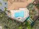 Aerial view featuring a large pool, spa, and bocce ball court surrounded by lush landscape near the community center at 1005 Indigo Run Ct, Spring Hill, FL 34609