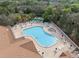 Aerial view of community pool surrounded by lounge chairs, manicured landscaping, and a bocce ball court at 1005 Indigo Run Ct, Spring Hill, FL 34609
