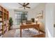 Bright home office with a ceiling fan, built-in shelving, and a large window with a view of the yard at 1005 Indigo Run Ct, Spring Hill, FL 34609