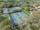 Aerial view of vibrant blue and red pickleball courts, surrounded by lush green trees and well-maintained tennis courts at 1005 Indigo Run Ct, Spring Hill, FL 34609