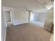 Open-concept living area with neutral walls, ceiling fan, carpet floors, and sliding glass door access at 10921 Stamford Dr, Port Richey, FL 34668