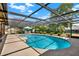 Sparkling pool in screened enclosure, surrounded by lush landscaping and seating area at 11256 Holbrook St, Spring Hill, FL 34609