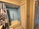 Bathroom with a blue tiled shower, neutral fixtures, closet, and entrance to another room at 11310 Carriage Hill Dr # 4, Port Richey, FL 34668