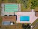 Aerial view featuring a community pool and shuffleboard courts and surrounding green spaces at 11735 Rolling Pine Ln, Port Richey, FL 34668