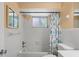 Cozy bathroom with shower-tub combo with white tile, window, and colorful shower curtain at 12613 Social Dr, Hudson, FL 34667