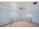 Serene bedroom with light blue walls, soft carpeting, and bright windows dressed with patterned curtains at 12613 Social Dr, Hudson, FL 34667