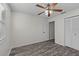 Bright bedroom featuring gray wood floors, ceiling fan, and closet for ample storage at 152 Chelsea Ct, Dunedin, FL 34698