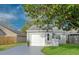 One-story home showcasing an attached garage with green grass and a paved driveway at 152 Chelsea Ct, Dunedin, FL 34698