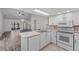Well-lit kitchen with white cabinets, tile backsplash, and modern appliances overlooking living area at 152 Chelsea Ct, Dunedin, FL 34698