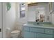 Cozy bathroom featuring a light blue vanity, toilet, and a decorative shell art piece at 2309 Terrace View Ln, Spring Hill, FL 34606