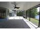Screened-in patio features a ceiling fan with views of the landscaped backyard and a tranquil lake at 23310 Cascade Pl, Land O Lakes, FL 34639