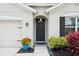 Welcoming front entry with a dark door, surrounded by lush plants, and a view of the garage at 30639 Summer Sun Loop, Wesley Chapel, FL 33545