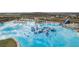 A large clear-water lagoon with a water playground, lounge chairs, and palm trees at 30639 Summer Sun Loop, Wesley Chapel, FL 33545