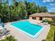 A sparkling community pool with lounge chairs surrounded by a black fence and lush landscaping and community building at 3142 Crenshaw Ct, New Port Richey, FL 34655