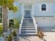 Inviting home entrance with staircase, front porch, garage, and lush tropical landscaping at 3215 Hibiscus Dr, Hernando Beach, FL 34607