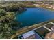 Aerial view featuring a serene lake bordered by mature trees, landscaping, and houses at 36419 Flats St, Zephyrhills, FL 33541