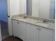 Bathroom featuring dual sinks with granite countertops, white cabinets, and an open doorway at 4009 Triggerfish Dr, Hernando Beach, FL 34607