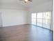 Bright living room with sliding glass doors leading to a balcony, featuring wood floors and neutral paint at 4009 Triggerfish Dr, Hernando Beach, FL 34607