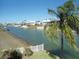 Scenic view of waterfront homes along a serene canal, framed by a lush palm tree at 4009 Triggerfish Dr, Hernando Beach, FL 34607